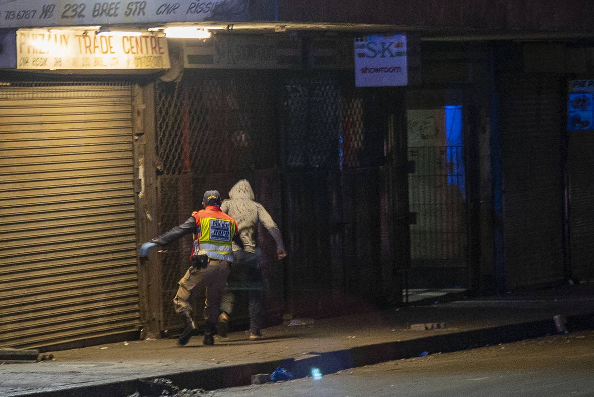 A police officer chases a man who violated the lockdown downtown Johannesburg, South Africa, Fr ...