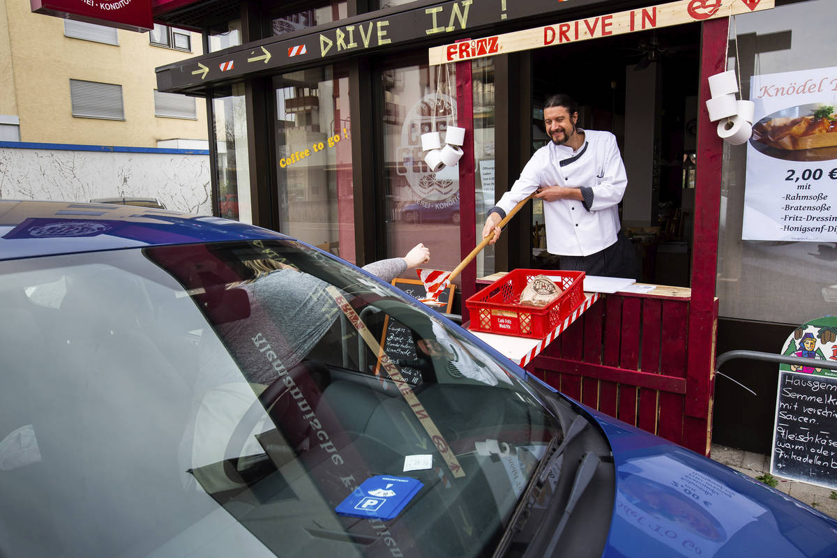Master baker Simon Fritz accepts cash from a customer at the window of the improvised drive-in ...