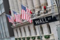 FILE - In this Jan. 3, 2020 file photo, the Wall St. street sign is framed by American flags fl ...
