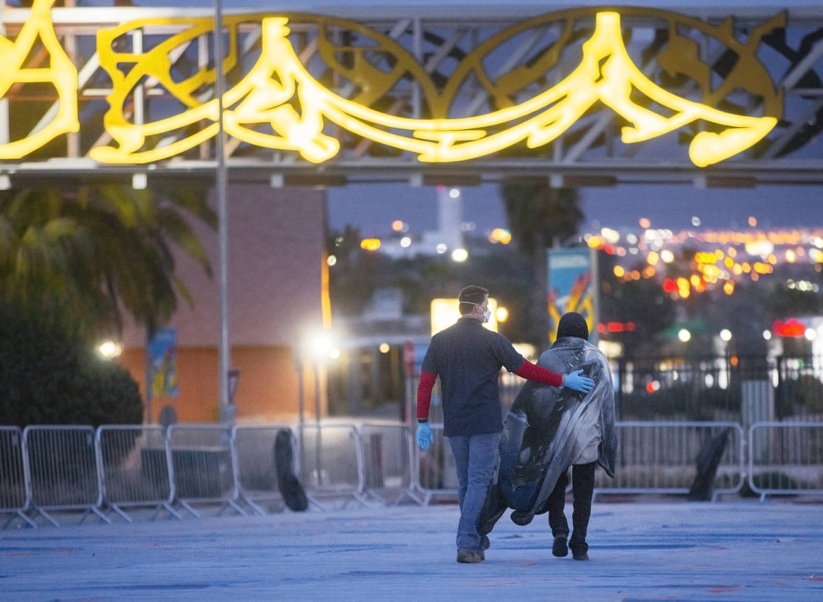 A volunteer helps find a homeless man a place to lay down at a temporary shelter for the homele ...