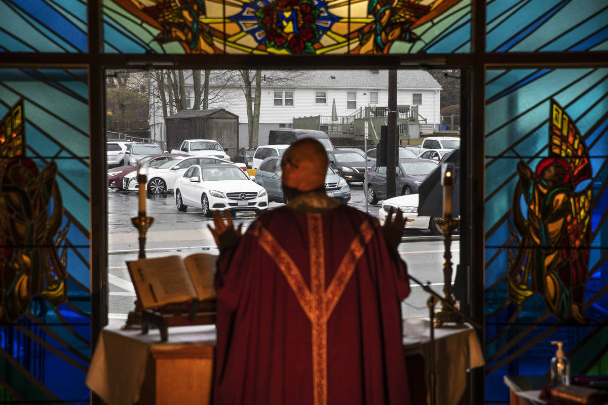 Rev. Peter Gower celebrates Mass from the front door of Our Lady of Grace Catholic Church as wo ...