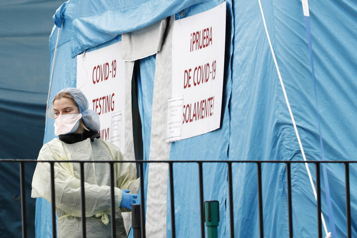 A medical worker prepares to reenter a COVID-19 testing tent set up outside Elmhurst Hospital C ...