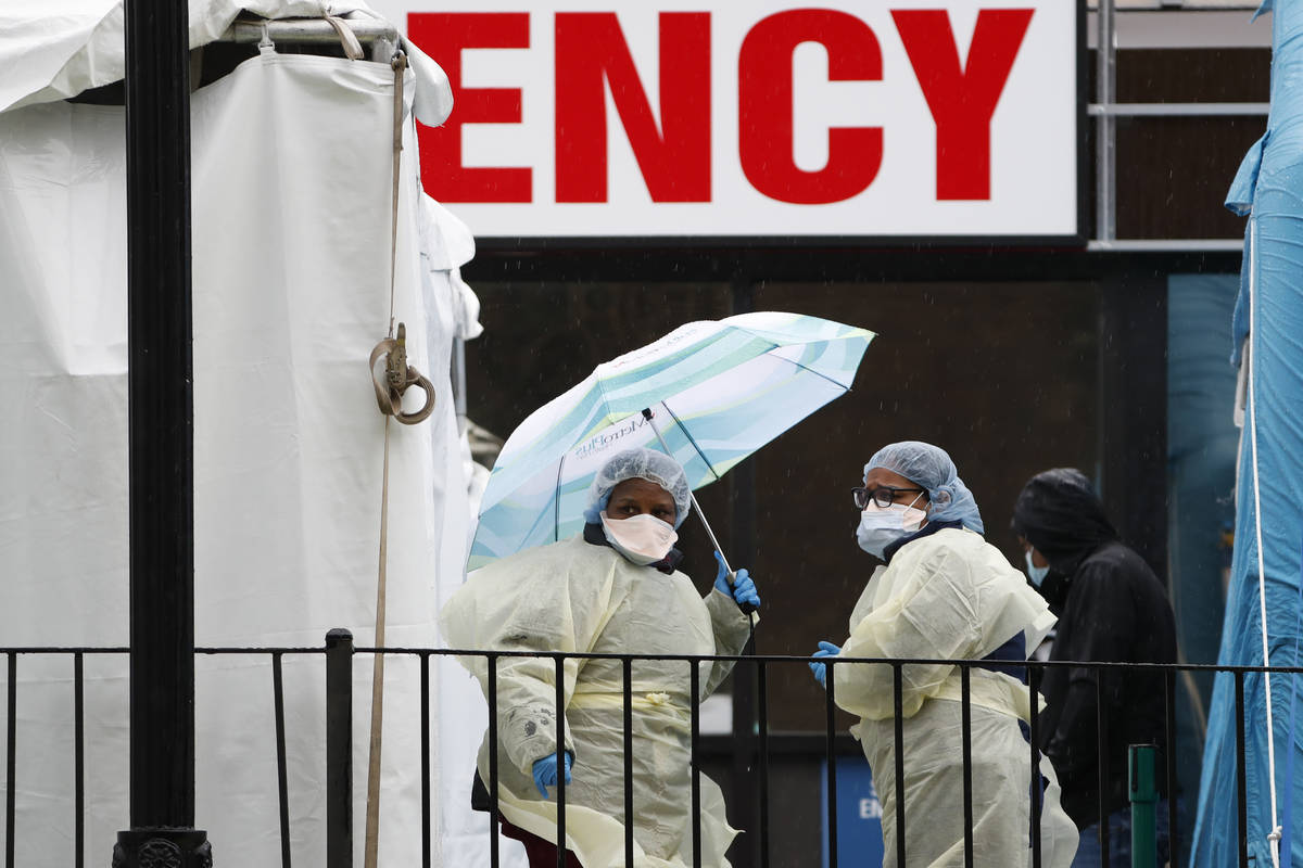 Two medical workers stand between COVID-19 testing tents set up outside Elmhurst Hospital Cente ...