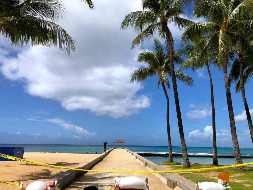 A man walks along a closed pier on Waikiki Beach in Honolulu on Saturday, March 28, 2020. (AP P ...