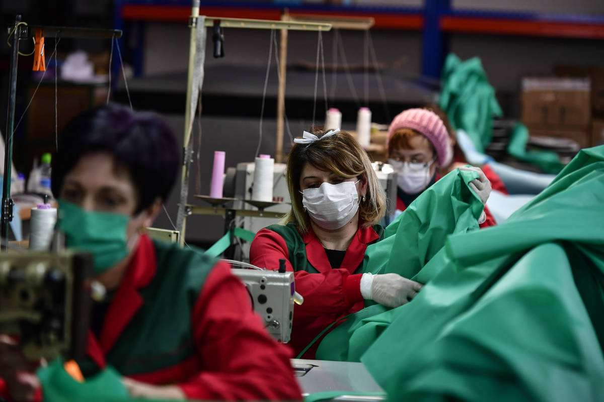 Volunteer workers in a clothing factory manufacturing firefighting gear, make hospital gowns fo ...