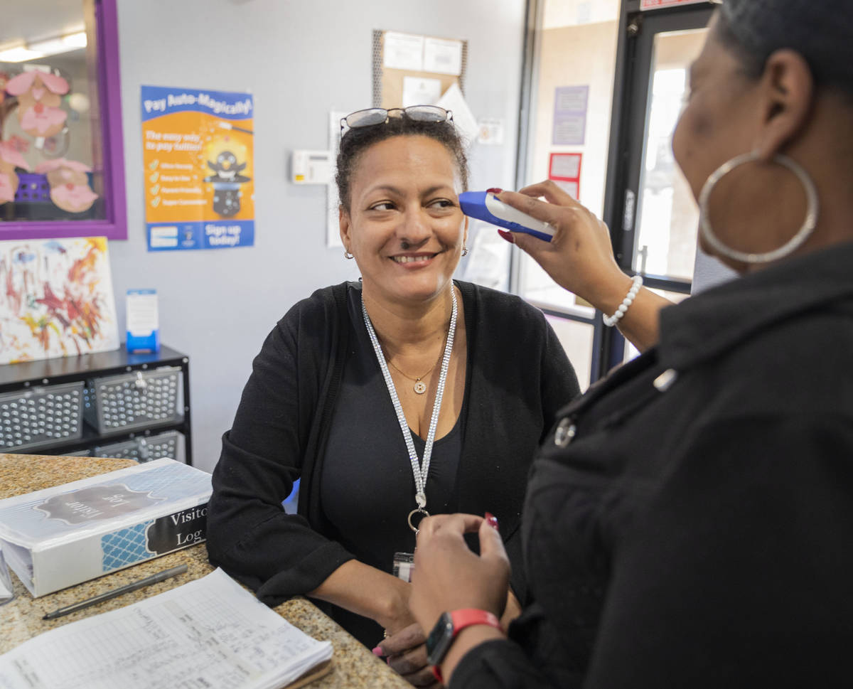 Discovery Gardens Childcare staff member Martha Valenzuela gets her temperature taken at the Bo ...