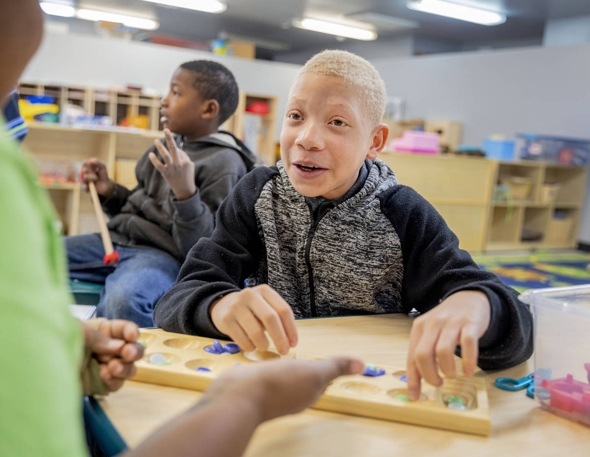 Nysir Darby, 10, plays a game with assistant teacher Nia Spinner in the school aged room at the ...