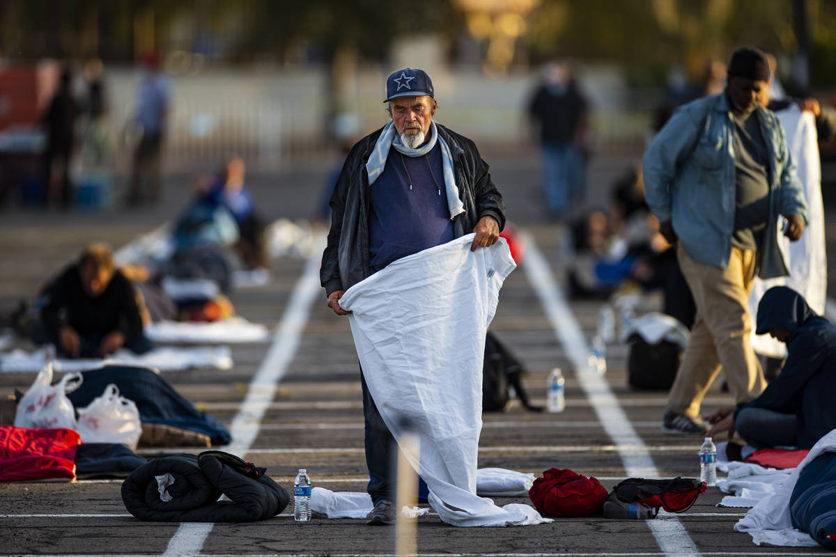 A homeless man sets up in an individual space at a temporary shelter in the upper parking lot a ...