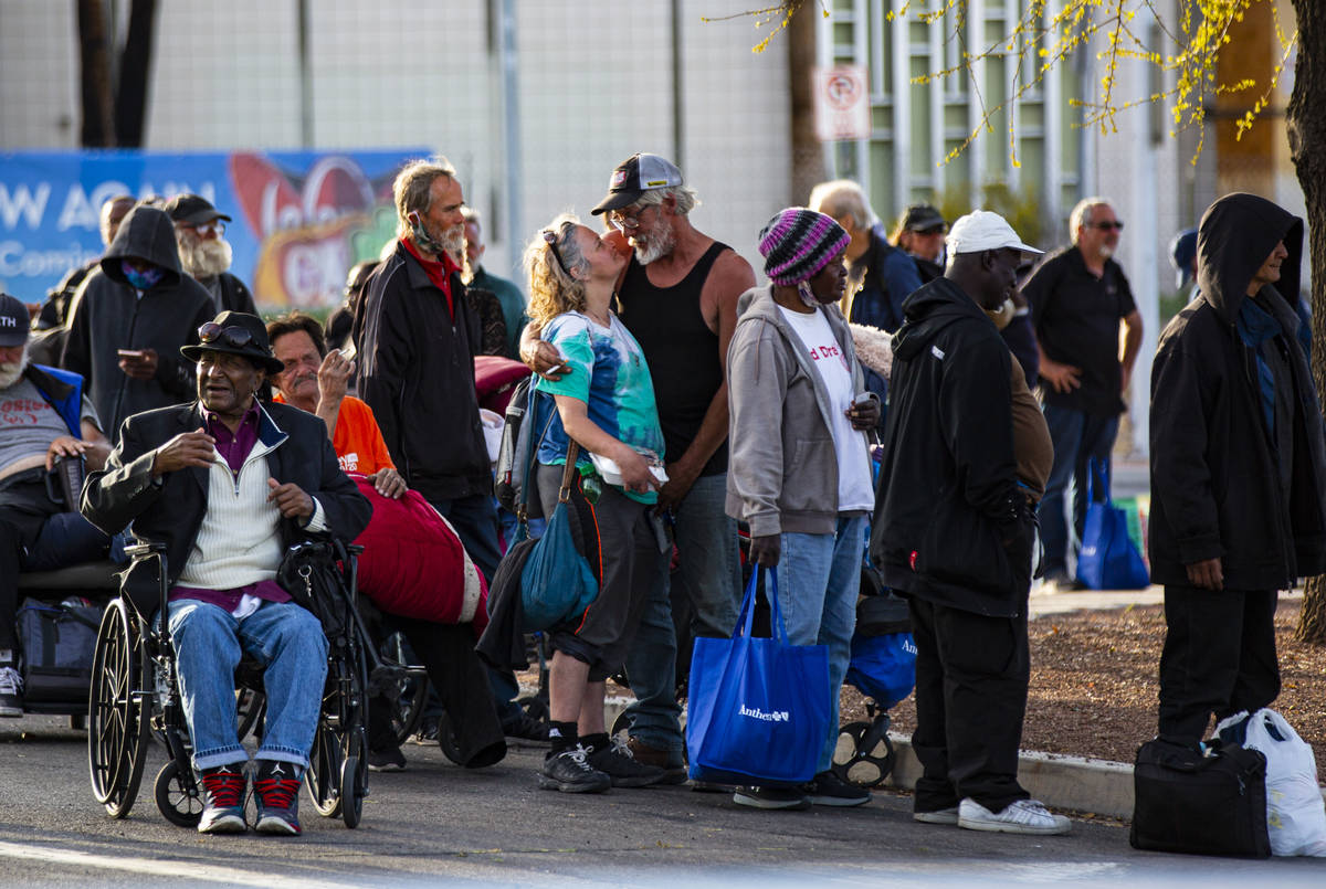 Homeless people line up to be screened to enter a temporary shelter in the upper parking lot at ...