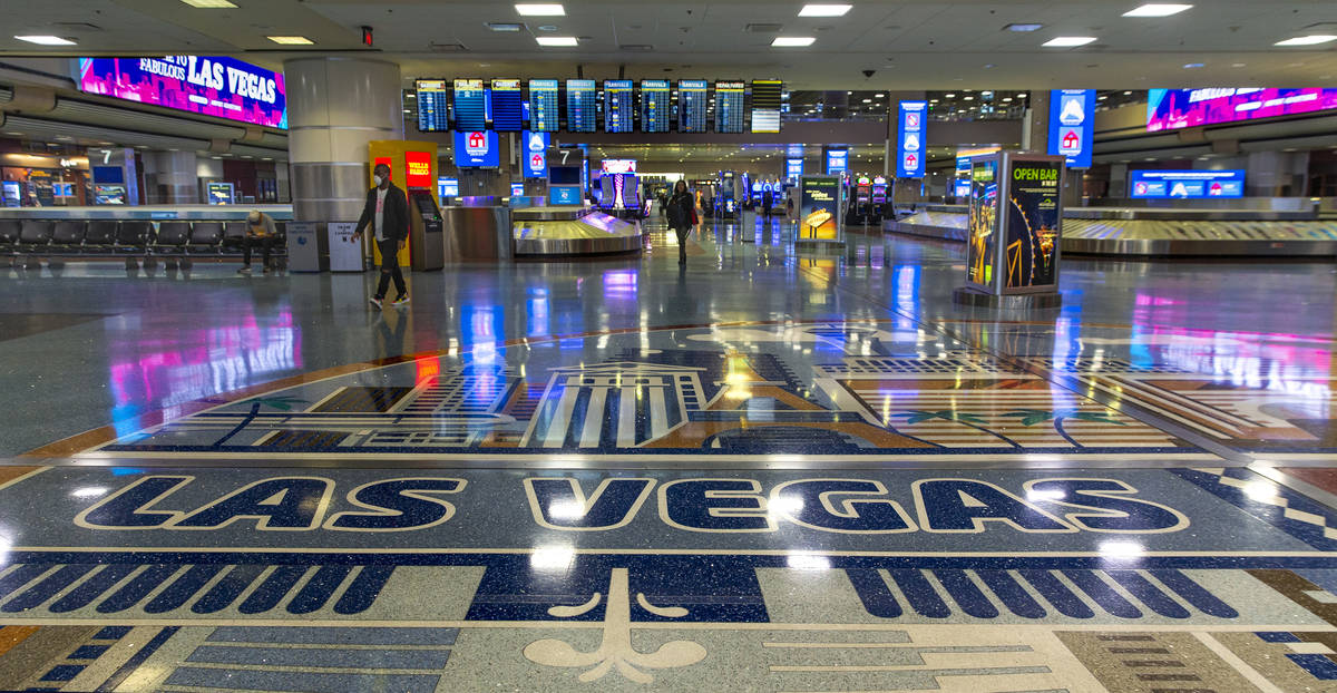 A masked passenger walks from the baggage area in Terminal 1 at McCarran International Airport, ...