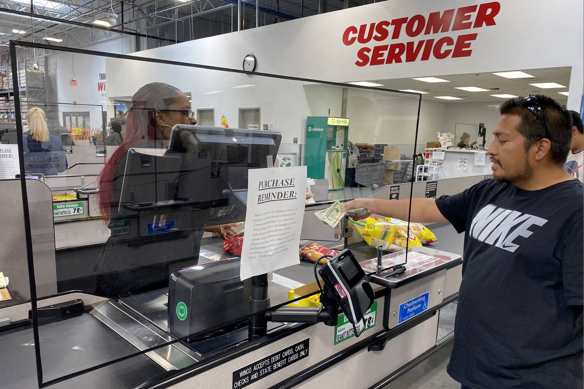 Cashiers work behind barriers at WinCo Foods at 7501 Washington Ave. in Las Vegas Tuesday, Marc ...