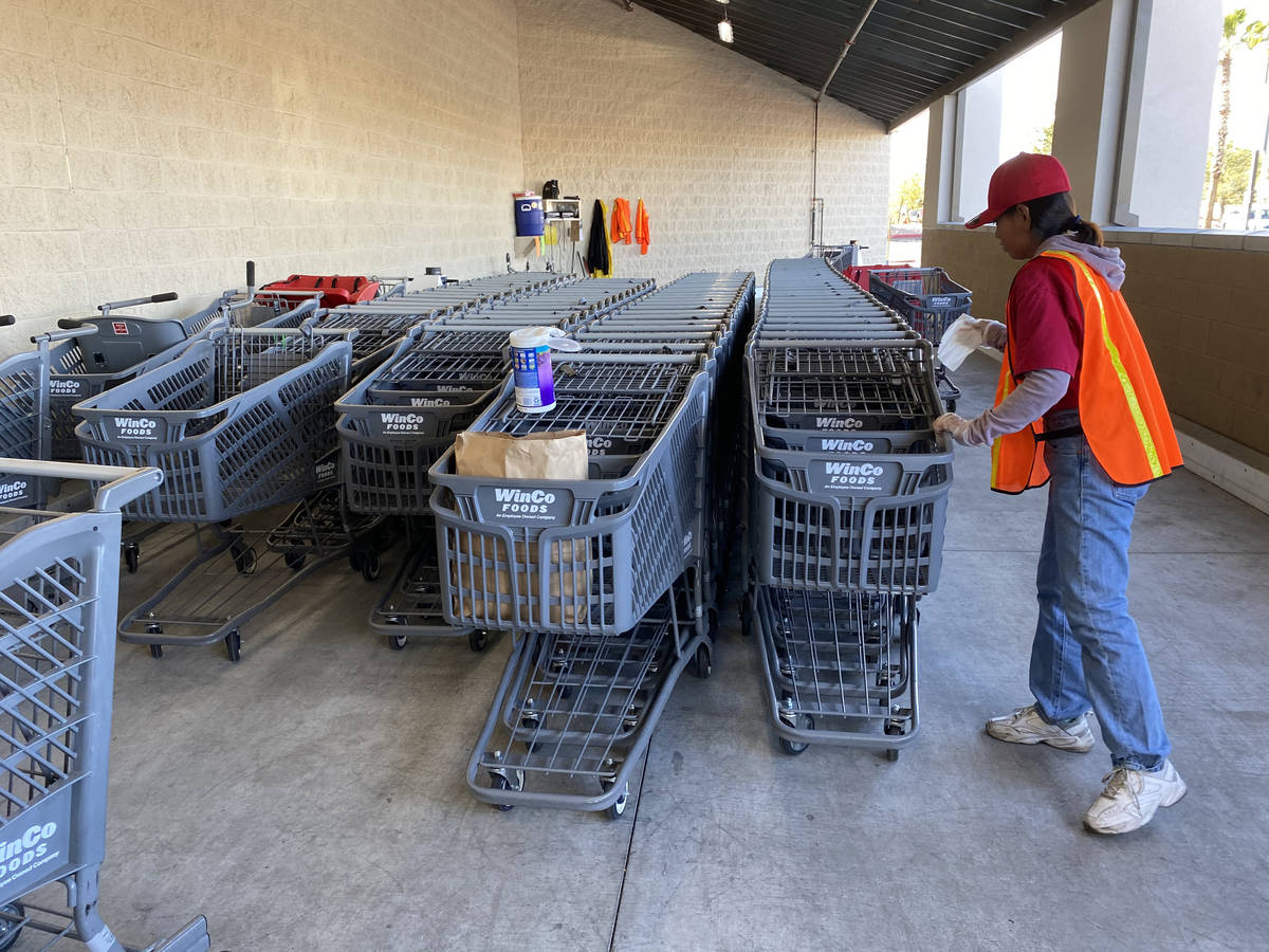A worker sanitizes carts at WinCo Foods at 7501 Washington Ave. in Las Vegas Tuesday, March 31, ...