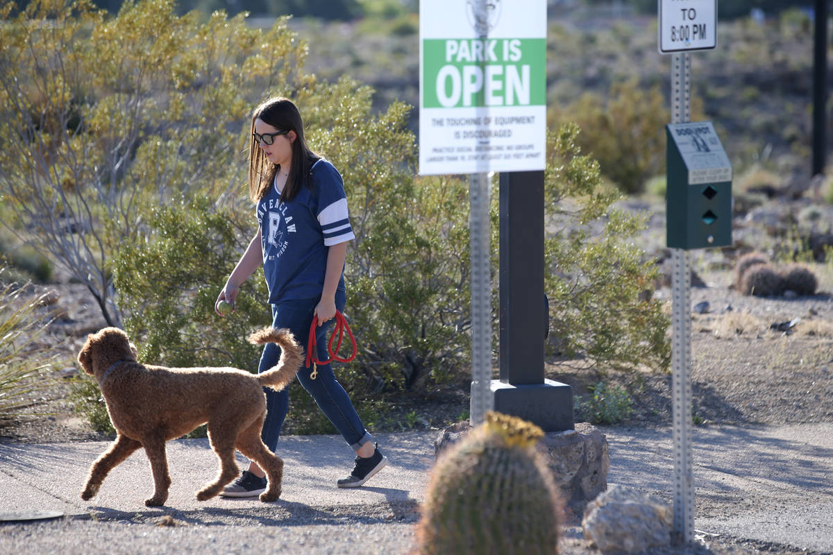 A woman walks her dog at Hualapai Canyon hiking area in Las Vegas Wednesday, April 1, 2020. (K. ...