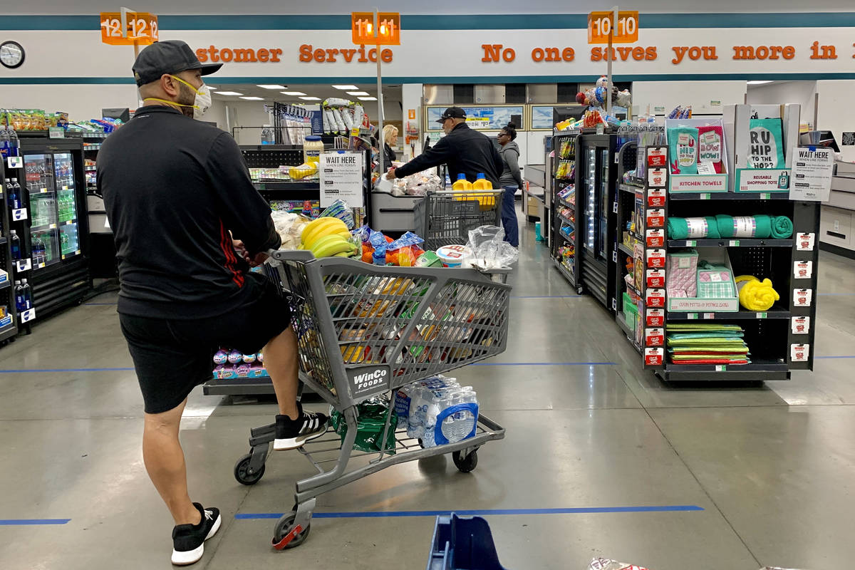 Shoppers wait in line practicing social distancing at WinCo Foods on N Stephanie Street in Hend ...