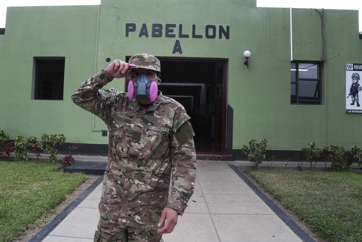 Wearing a face mask he brought from home, a military reservist stands outside his sleeping barr ...