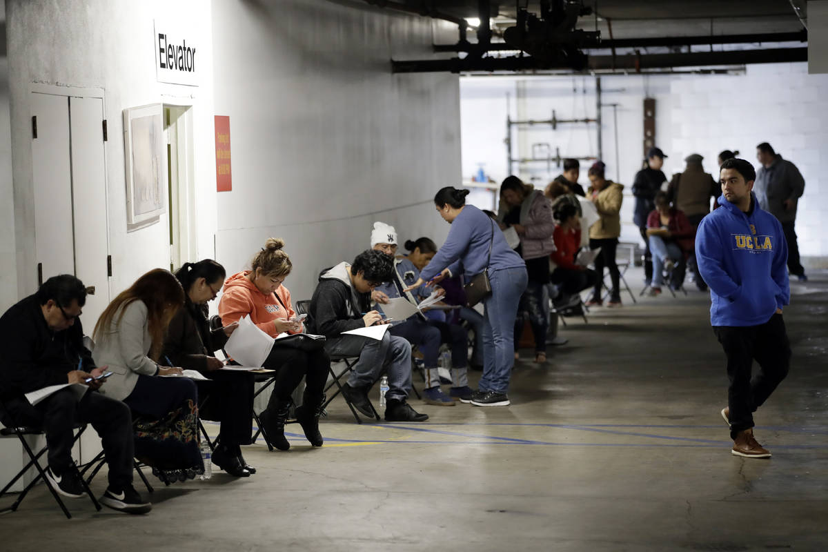 Unionized hospitality workers wait in line in a basement garage to apply for unemployment benef ...