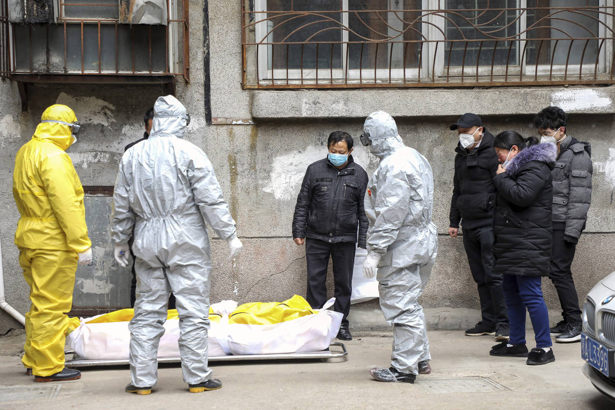 In this Feb. 1, 2020, file photo, funeral home workers remove the body of a person suspected to ...