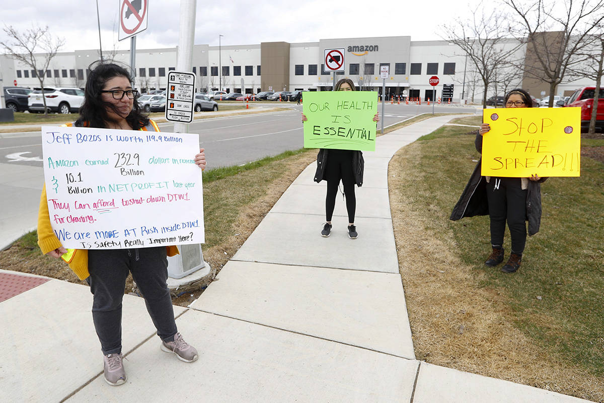 Breana Avelar, left, a processing assistant and family members, hold signs outside the Amazon D ...