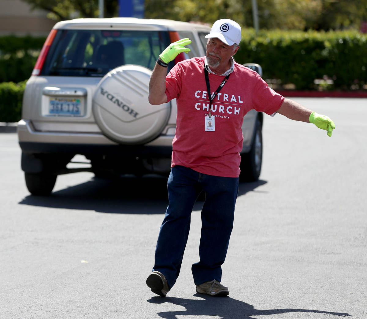 Three Square Food Bank volunteer Norman Fultz directs people in their cars waiting to receive f ...