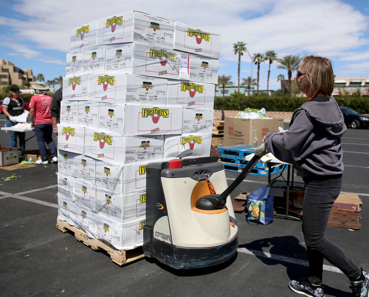 Three Square Food Bank warehouse assistant Kari Guerrero moves boxes of fresh fruit to give out ...