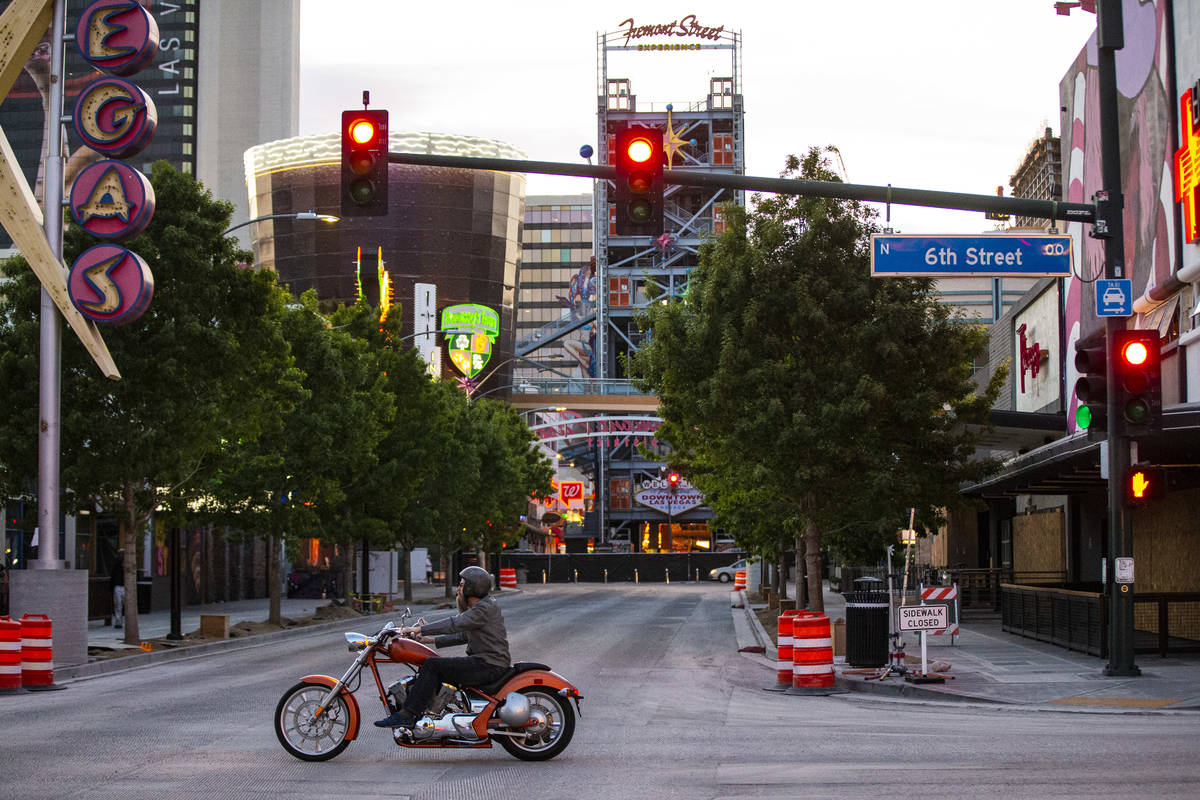 A man rides a motorcycle along 6th Street past Fremont Street as traffic remains light in the w ...