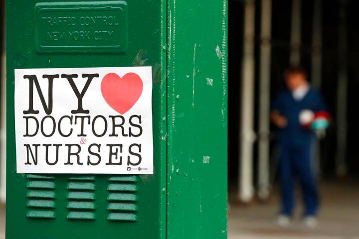 A sign acknowledging the work of doctors and nurses is posted on a traffic control box outside ...