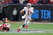 Ohio State quarterback Justin Fields (1) runs with the ball past Wisconsin defensive end Isaiah ...