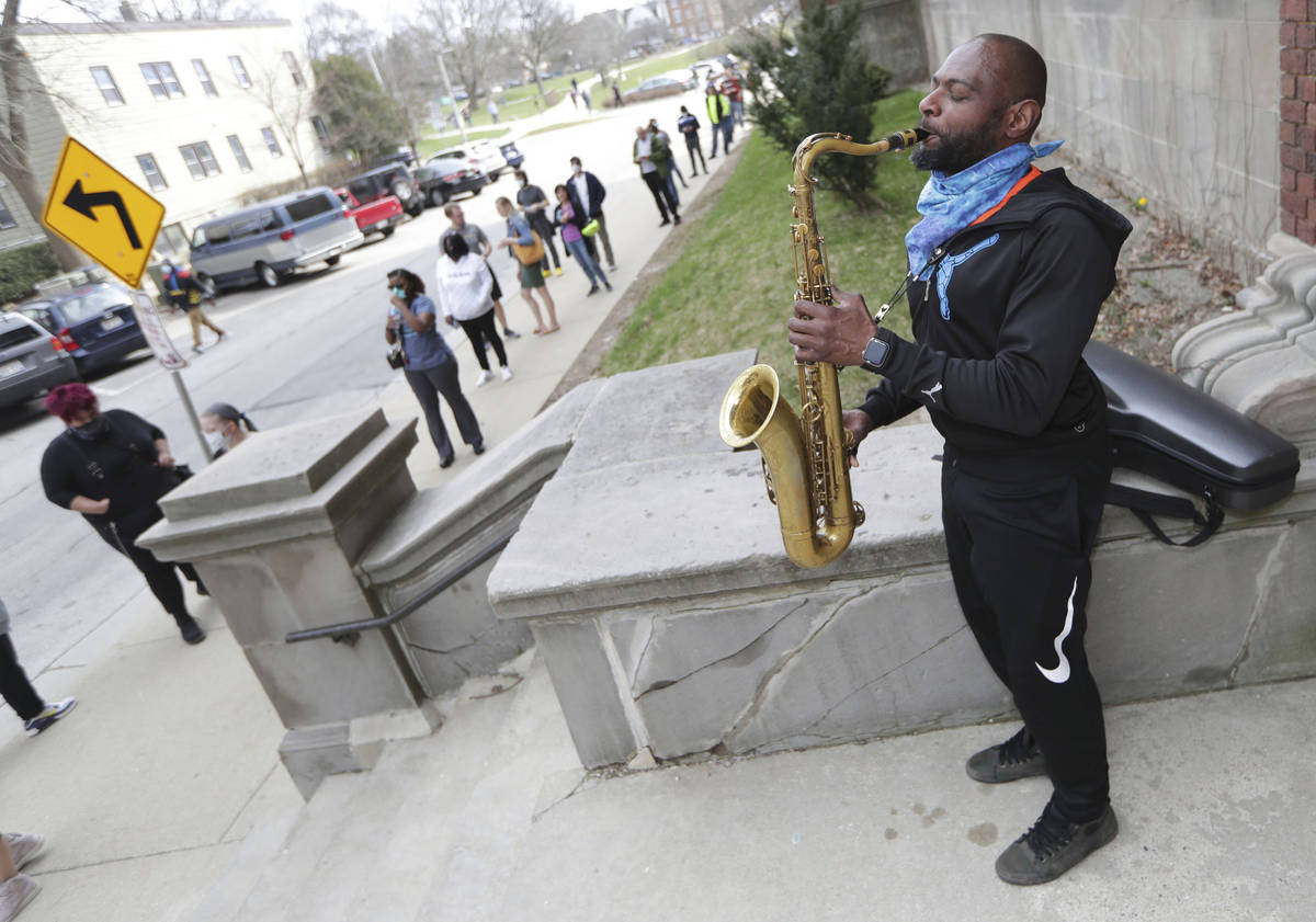 Olu Sijuwade, of Milwaukee, plays a tenor saxophone for those waiting in line to vote at Rivers ...