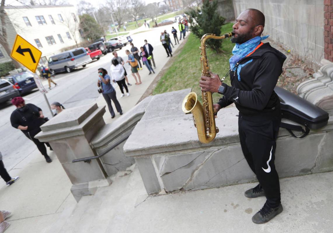 Olu Sijuwade, of Milwaukee, plays a tenor saxophone for those waiting in line to vote at Rivers ...