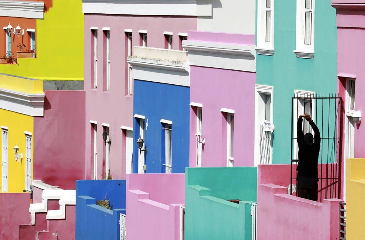 A man stretches, at the entrance of his home in Bo-Kaap, Cape Town, South Africa, Tuesday, Apri ...