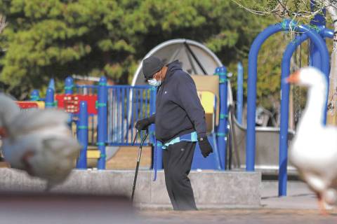 A man, who declined to give his name, wears protective masks as he walks at Sunset Park on Wedn ...