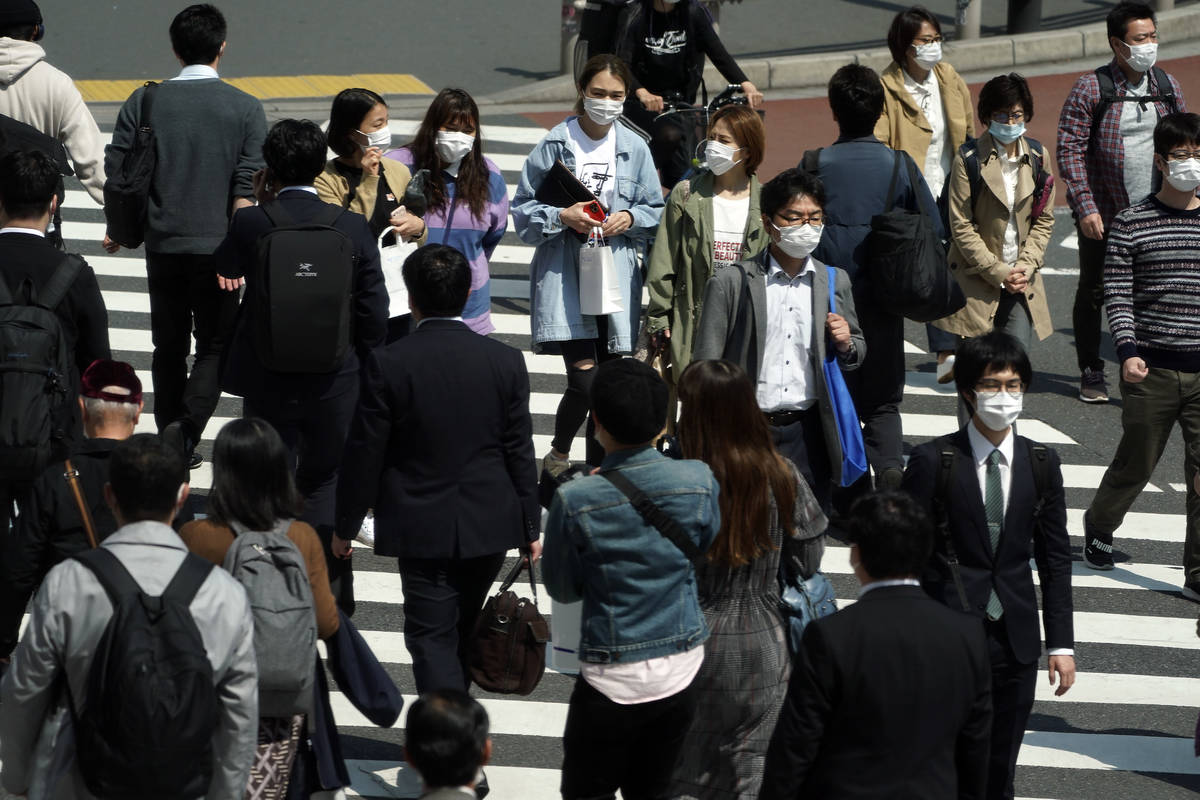 People with protective masks cross a pedestrian walkway Thursday, April 9, 2020, in Tokyo. Japa ...