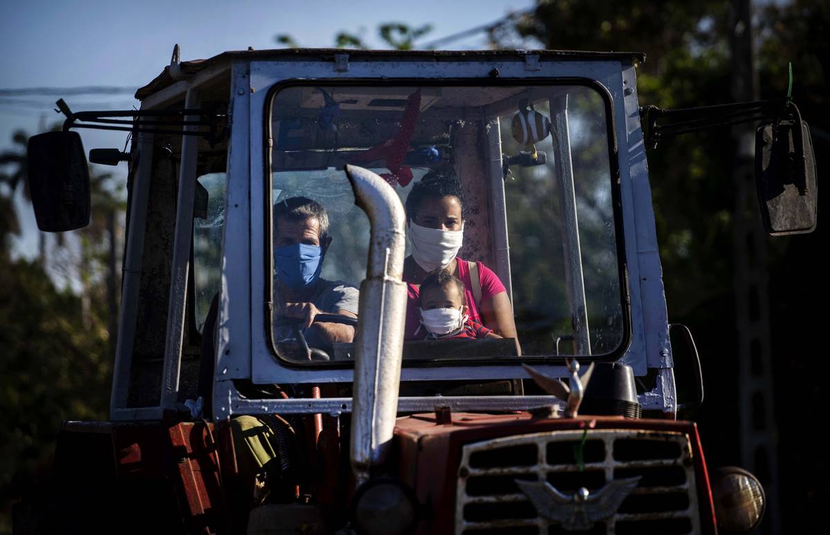 A family rides their tractor through the countryside wearing masks as a precaution against the ...