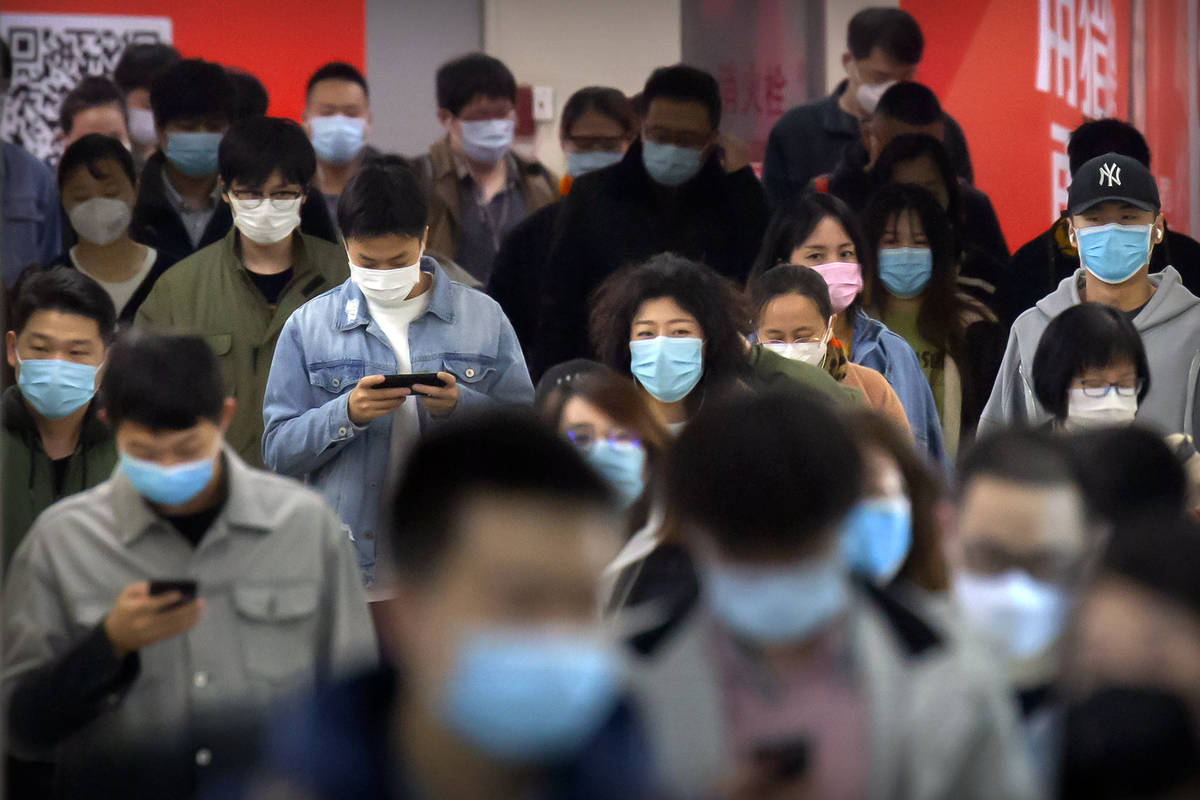 Commuters wear face masks to protect against the spread of new coronavirus as they walk through ...