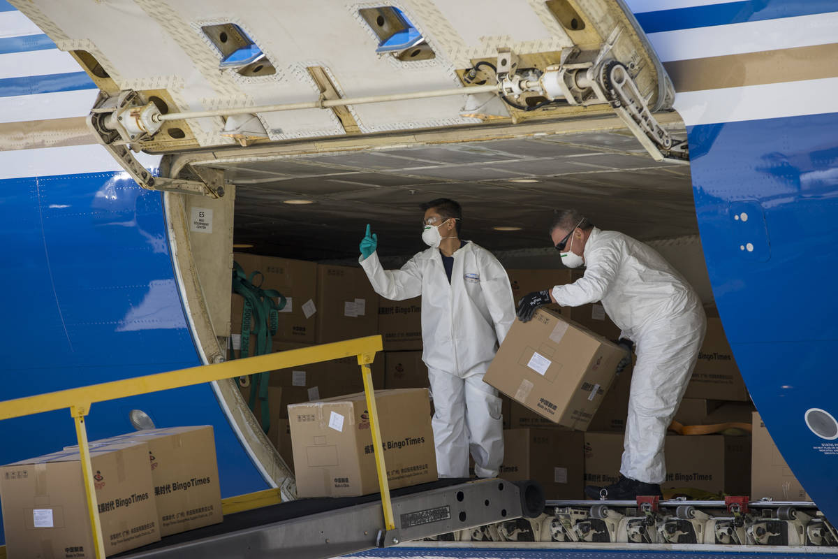 Transport workers unload some of the 1 million surgical masks arriving from Guangzhou, China, a ...