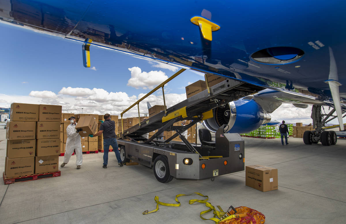 Transport workers unload some of the 1 million surgical masks arriving from Guangzhou, China, a ...