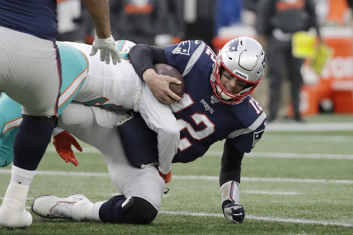 Miami Dolphins defensive end Trent Harris, left, sacks New England Patriots quarterback Tom Bra ...