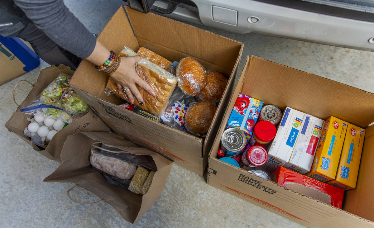 Kat Morris divides up food and supplies for another donation drop with the COVID-19 Barter Grou ...