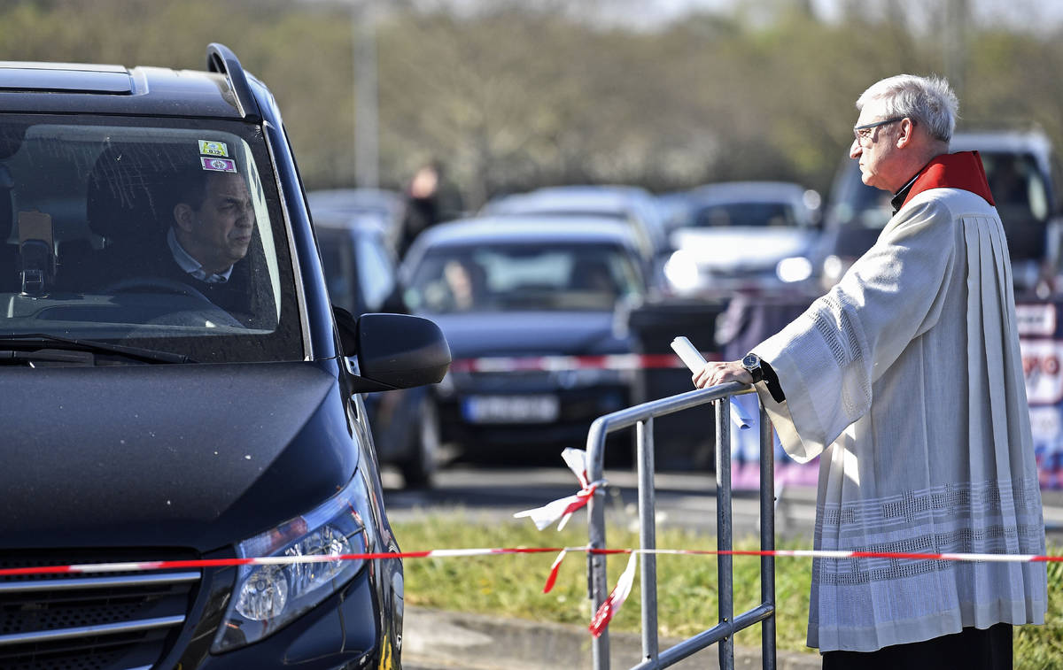 Priest Frank Heidkamp talks to believers in their cars prior a Good Friday church service at a ...