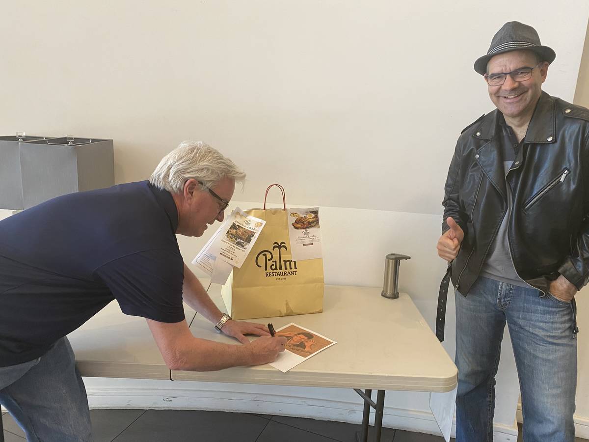 Palm Restaurant GM Michael Martin signs a sketch of R-J columnist John Katsilometes during a de ...