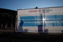 A worker casts a shadow on a sign with guidelines for protection from COVID-19 as construction ...