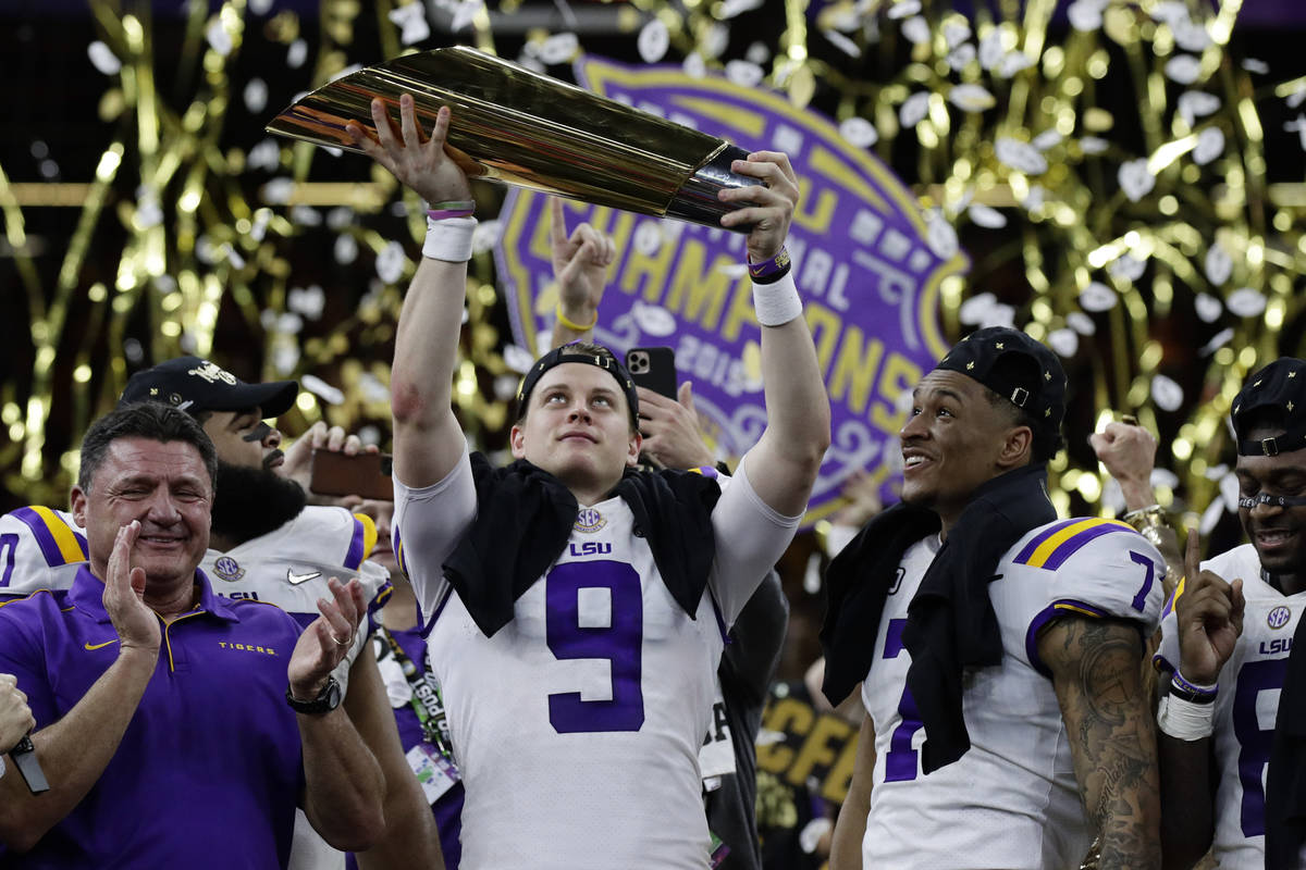 LSU quarterback Joe Burrow holds the trophy as safety Grant Delpit looks on after a NCAA Colleg ...