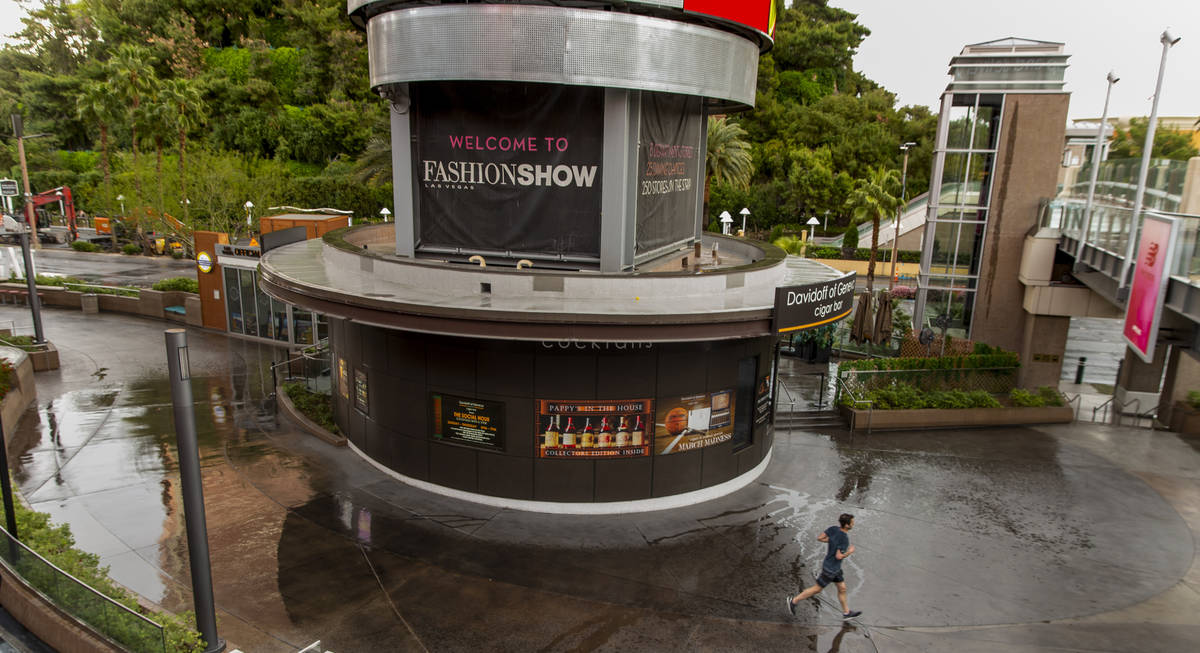 A runner moves in and out of the rain about the Fashion Show mall along the Las Vegas Strip on ...