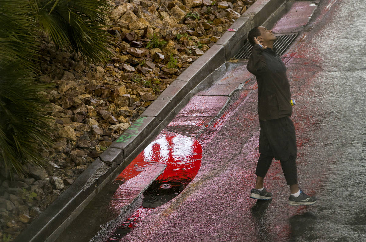 A pedestrian looks up to the rain as he walks past the Fashion Show mall along the Las Vegas St ...