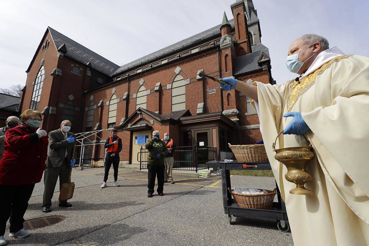 Rev. William Schipper, pastor of Mary, Queen of the Rosary Parish, right, wears a mask and glov ...