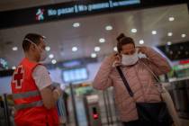A passenger receives a face mask distributed by a red cross volunteer at the main train station ...