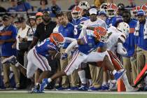 Miami wide receiver Jeff Thomas (4) is knocked out of bounds by Florida linebacker David Reese ...