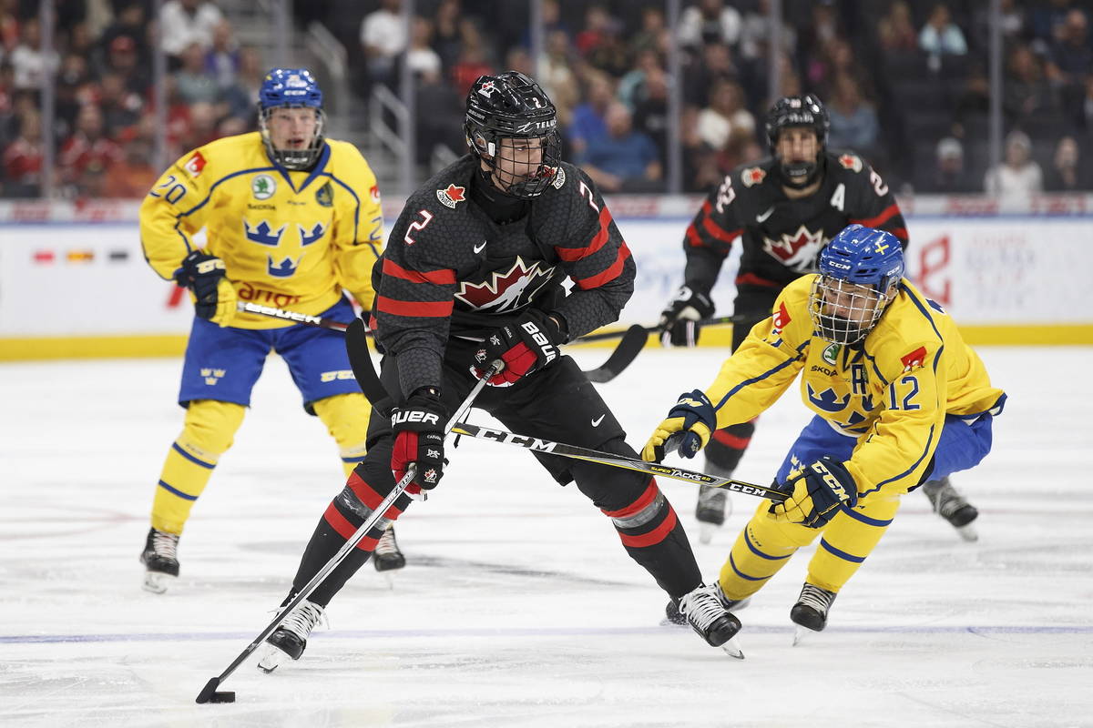 Canada's Justin Barron (2) is pursued by Sweden's Karl Henriksson (20) and Arvid Costmar (12) d ...