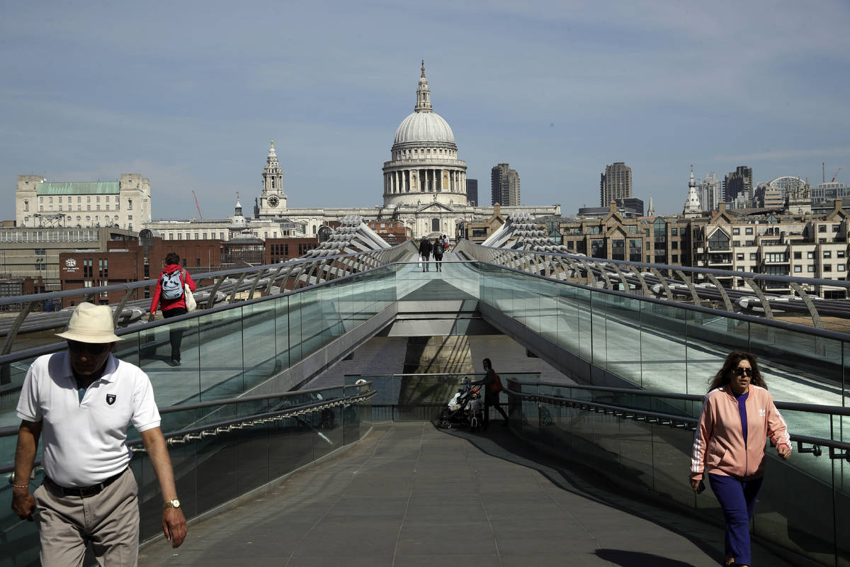 People space out to observe social distancing, on the Millennium Bridge backdropped by St Paul' ...