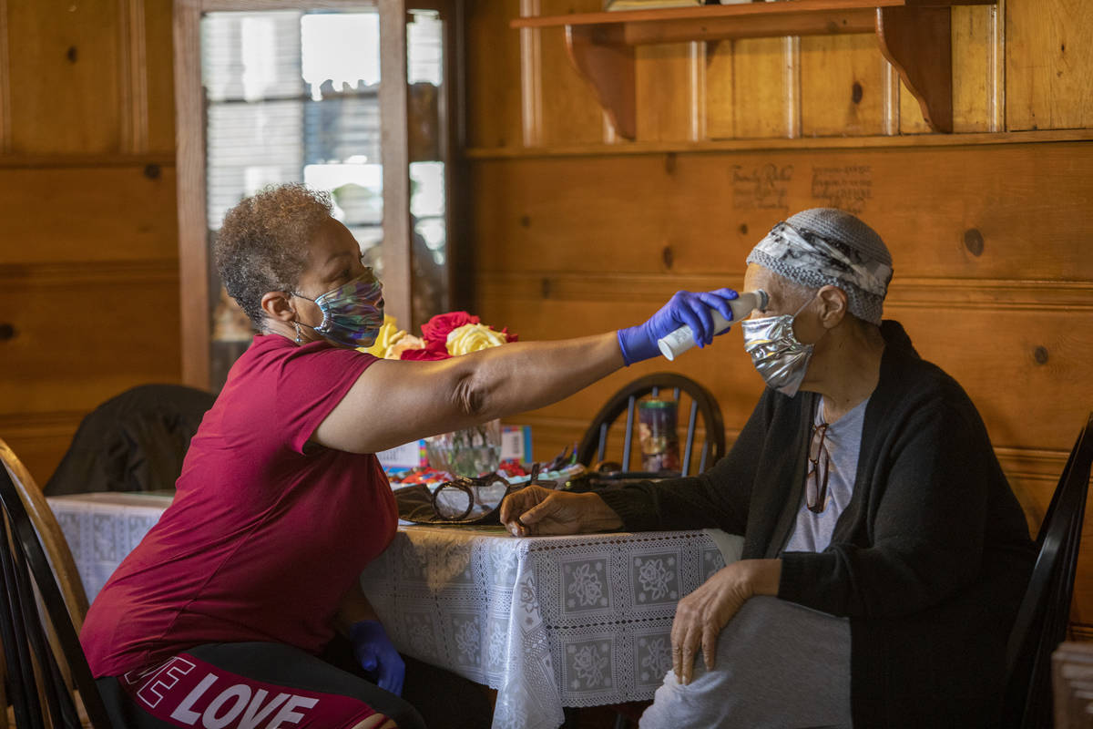 Kismet Evans takes the temperature of her mother, Pauline Evans, at their kitchen table on Thur ...